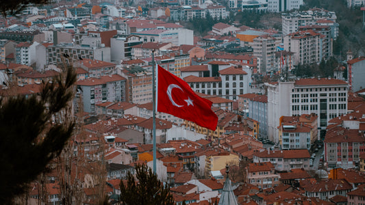 Aerial view of a Turkish city with a Turkish flag flying above red-tiled rooftops