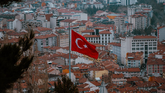 Aerial view of a Turkish city with a Turkish flag flying above red-tiled rooftops