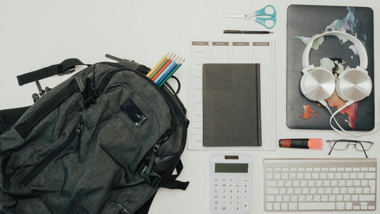 Flat lay of a gray backpack surrounded by school and office supplies for a bulk donation program