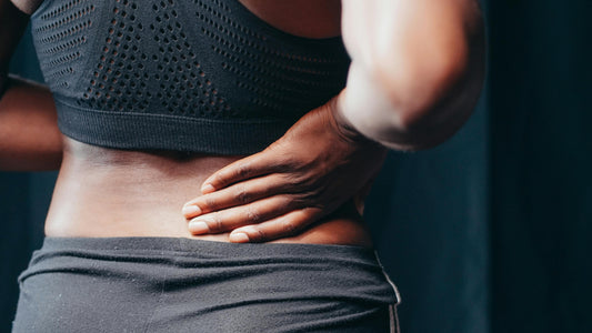 Close-up of a person holding their lower back in discomfort