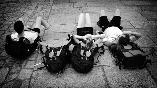 Travelers resting with backpacks on a cobblestone street
