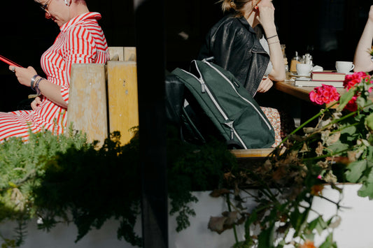 Dark green laptop backpack leaning against a chair at an outdoor cafe table