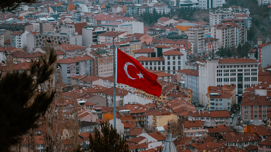 Aerial view of a Turkish city with a Turkish flag flying above red-tiled rooftops