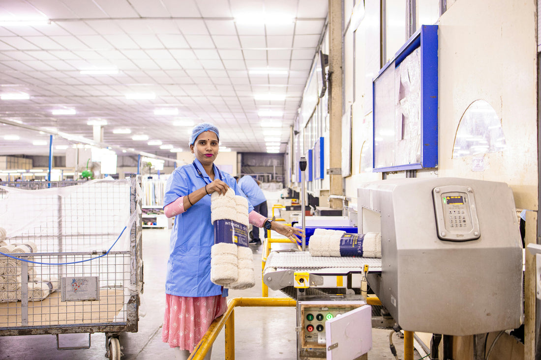 Factory worker inspecting rolled textile products on a production line for quality control