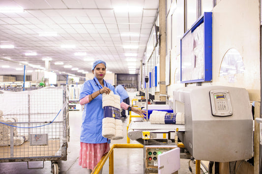 Factory worker inspecting rolled textile products on a production line for quality control