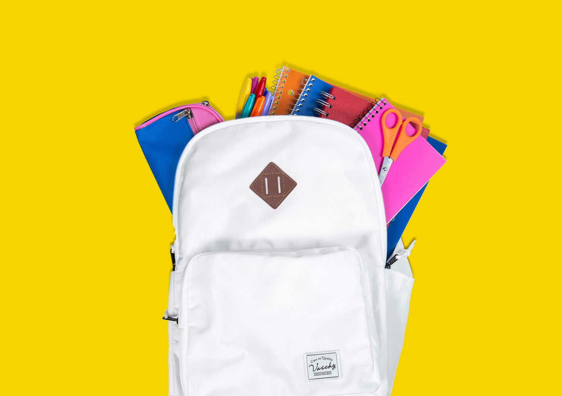 White backpack sample open to show colorful school supplies against a yellow background