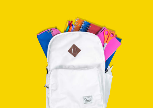 White backpack sample open to show colorful school supplies against a yellow background