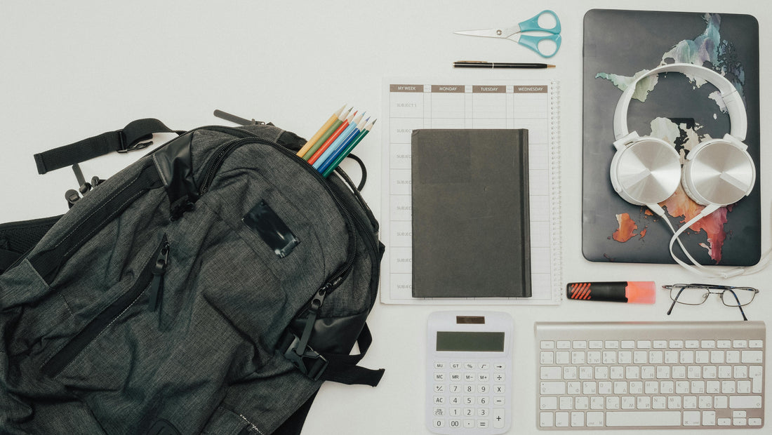 Flat lay of a gray backpack surrounded by school and office supplies for a bulk donation program
