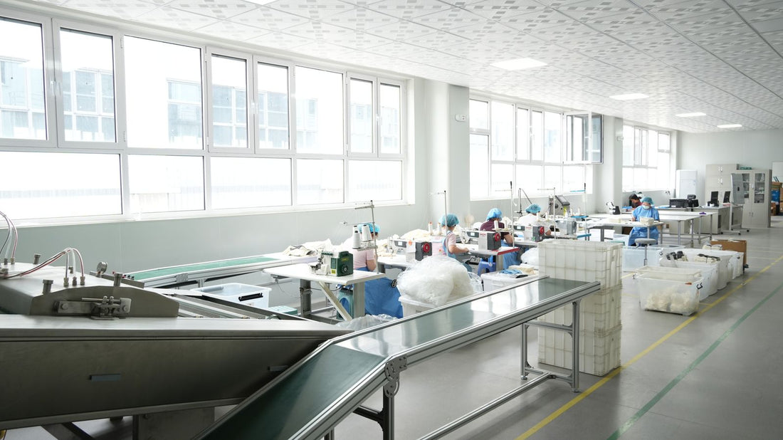Bright factory interior with workers at sewing stations producing sample backpacks