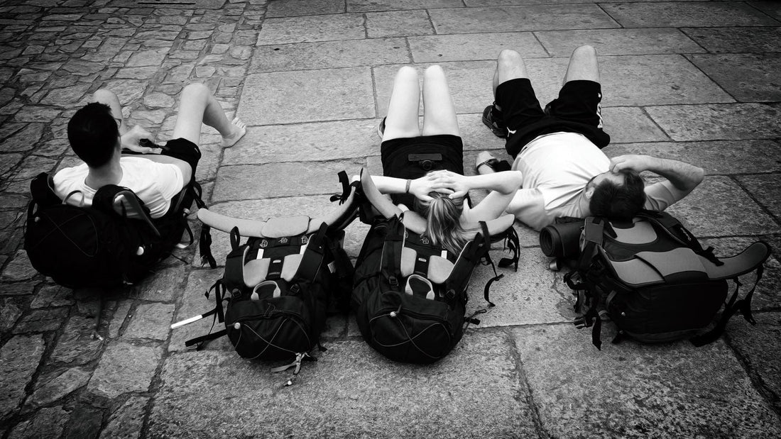 Travelers resting with backpacks on a cobblestone street