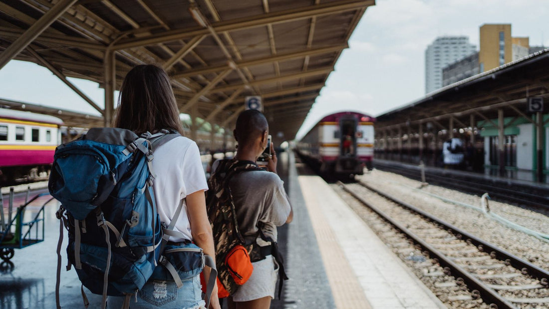 Two travelers with backpacks waiting at a railway station
