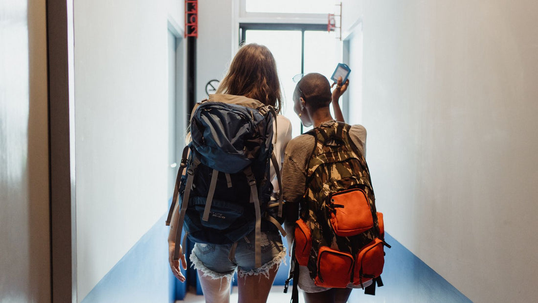 Two students with backpacks walking through a hallway