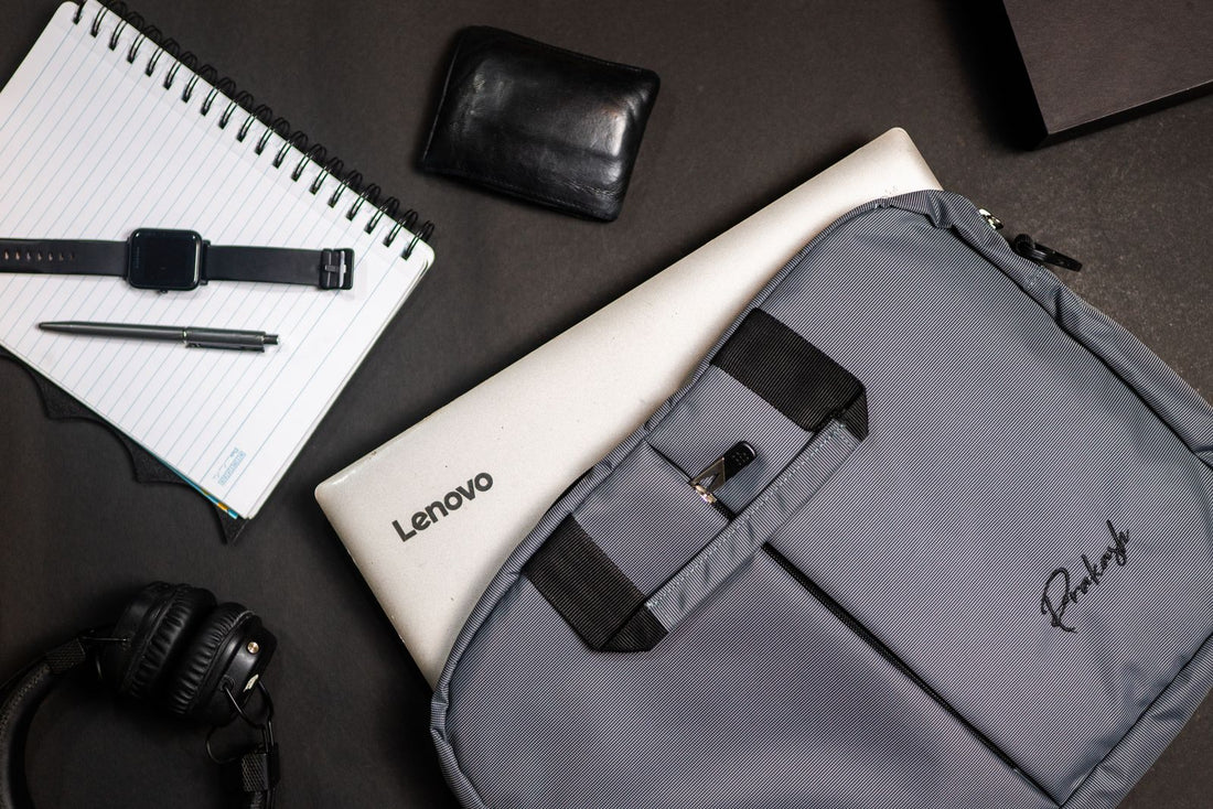 Laptop, grey backpack, and everyday tech accessories arranged in a flat-lay workspace setup, representing wholesale gear for tech company teams.