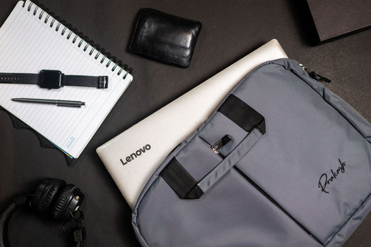 Laptop, grey backpack, and everyday tech accessories arranged in a flat-lay workspace setup, representing wholesale gear for tech company teams.