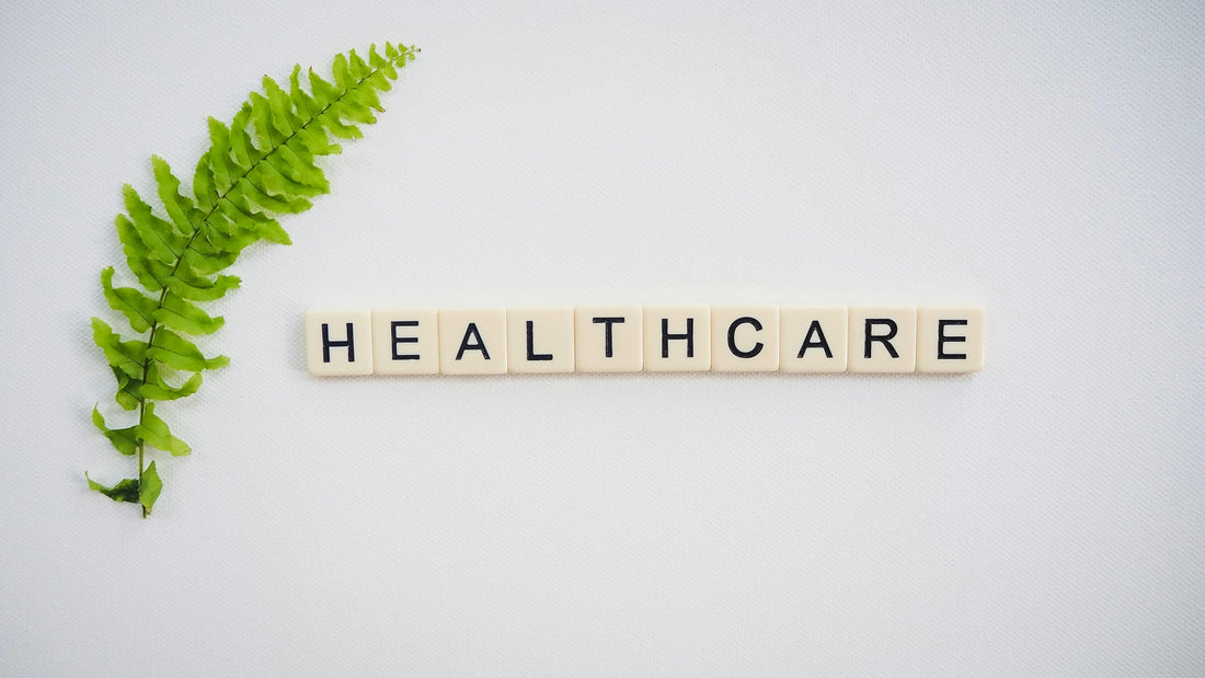The word HEALTHCARE spelled in letter tiles next to a green fern leaf