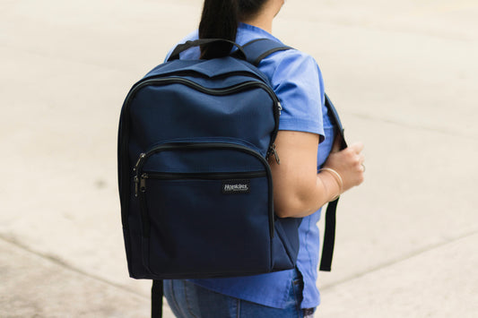 Healthcare worker in scrubs wearing a navy ergonomic backpack, rear view